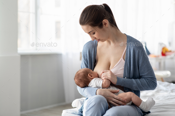 Beautiful Young Mother Breastfeeding Baby And Smiling At, 50% OFF