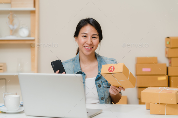 Asian young entrepreneur business woman owner of SME checking product on stock scan qr code.