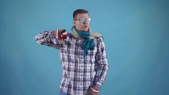Distressed Frozen Man Covered with Frost in Gloves and Scarf on Blue Background Shows Finger Down alt