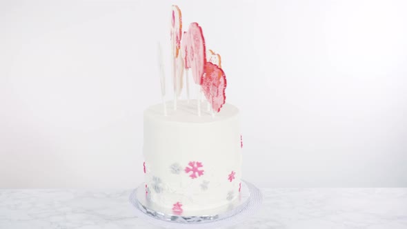Tall Round Cake with Italian Buttercream Frosting Decorated with Fondant Snowflakes and Topped with alt
