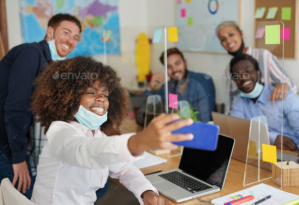 Multiracial people in coworking office taking a selfie while wearing surgical face mask under chin