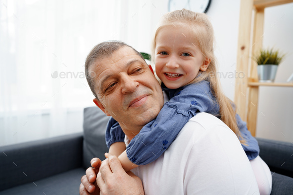 Grandpa And Little Granddaughter Sitting On Sofa At Home Stock Photo By 