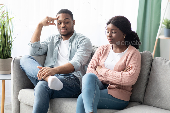 Frustrated black woman sitting apart from her frustrated boyfriend
