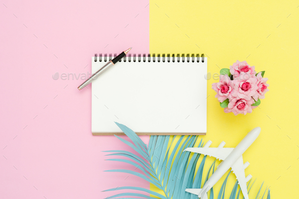 Top view mockup of blank paper notebook, pen, pastel coconut leaf and plane.