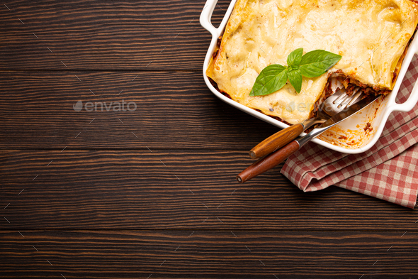Traditional Italian lasagna in casserole pan on wooden table - Stock Photo - Images
