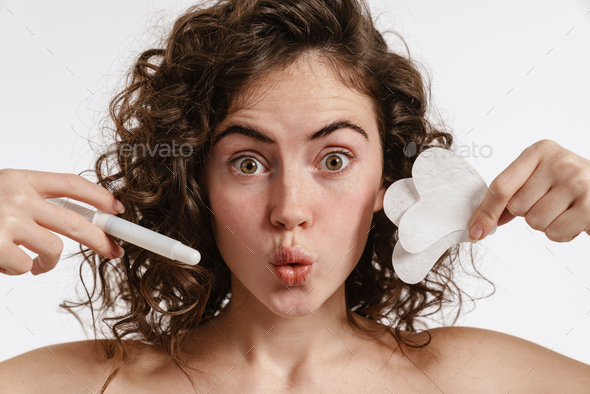 Surprised shirtless girl grimacing while posing with cosmetic devices