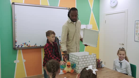 An African American Teacher Teaches a Group of Children English By Playing with Them alt