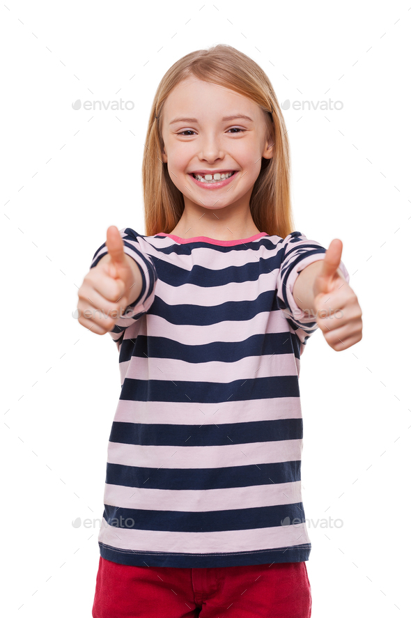 Happy little girl. Cheerful little girl showing her thumbs up while ...