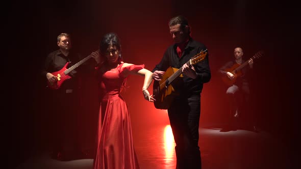 Flamenco Dance Performed By a Professional Girl Next To Playing Guitarists Music. Light From Behind alt