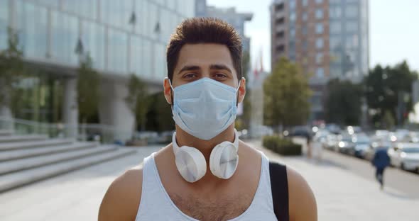 Portrait of Indian Man Wearing Protective Face Mask Standing in City and Looking at Camera alt