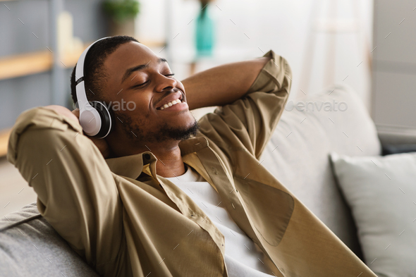 African American Man Listening To Music Wearing Earphones At Home