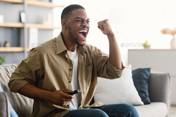 Emotional African Man Watching Sports On TV Celebrating Victory Indoor