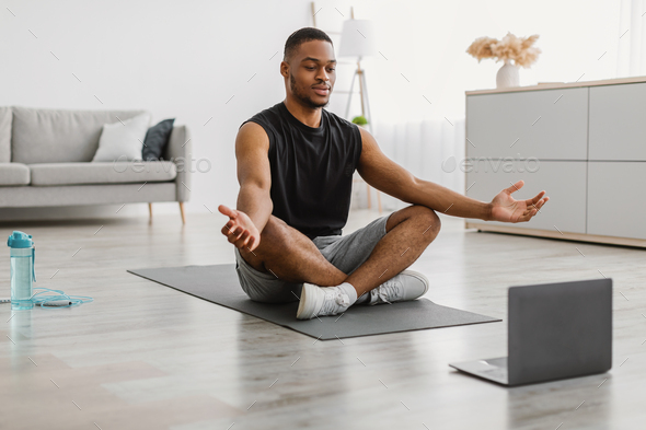 African American Guy Doing Yoga At Laptop Meditating At Home