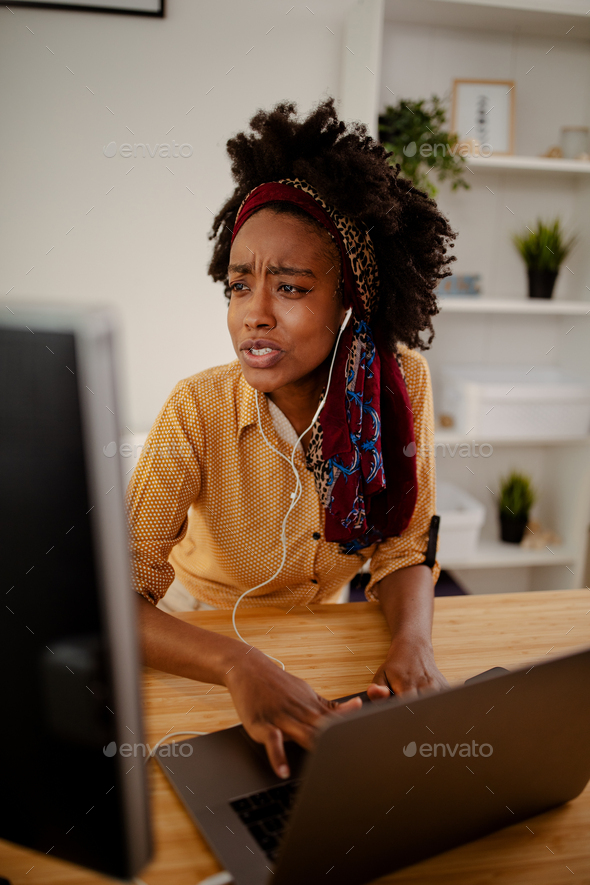 Black woman designer with earphones having video call and discuss