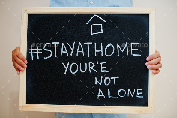 Stay home hashtag, you are not alone. Coronavirus concept. Boy hold inscription on the board.