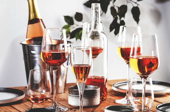 Rose wine glasses and bottles on table served for festive dinner party  Stock Photo by Olga_Kochina