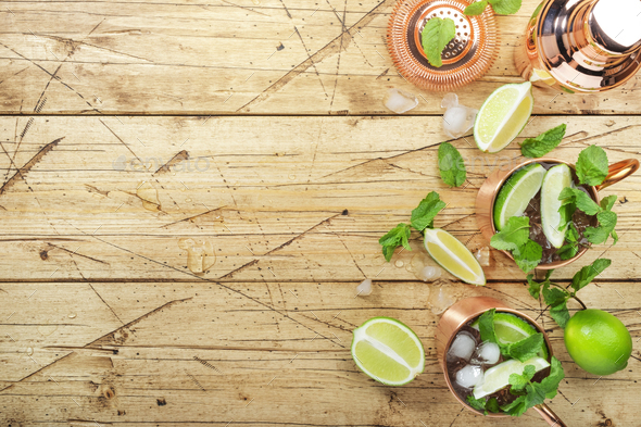 Moscow mule cocktail in copper mug with lime, ginger beer, vodka and mint. Wooden bar counter - Stock Photo - Images