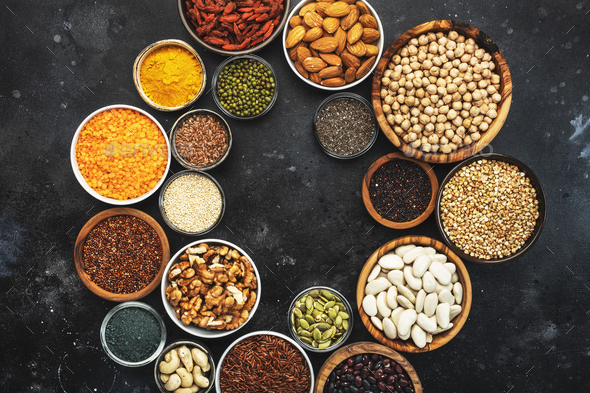 Selection of superfoods, legumes, cereals, nuts, seeds in bowls on black background - Stock Photo - Images