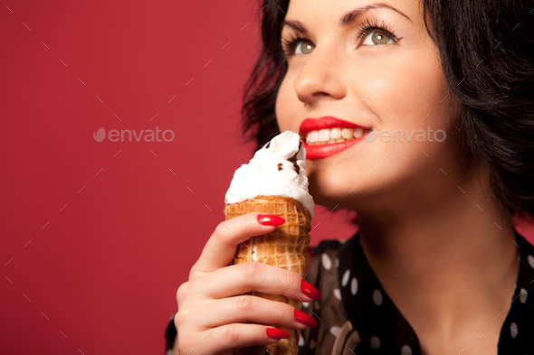 Young woman with red lips eating ice cream over red background
