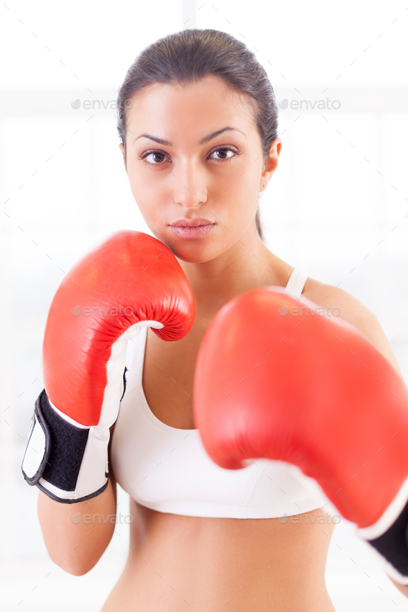 Woman boxing. Confident young woman in boxing gloves looking at camera