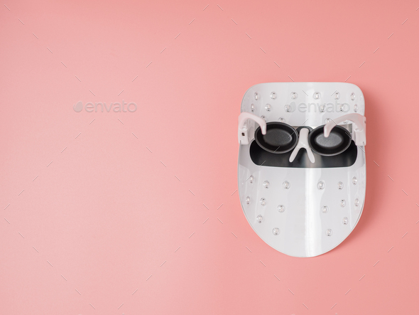 Led light face mask on pink background, copy space