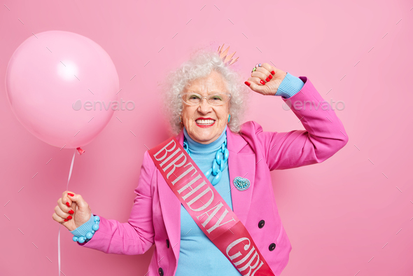 Carefree grey haired wrinkled woman dances carefree smiles positively dressed in festive clothes wea