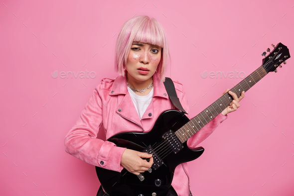 Serious fashionable woman starts career as rock star performs music on black acoustic guitar prepare