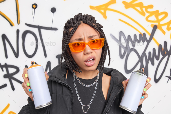 cache mus eller rotte Ripples Discontent indignant teenage girl with dreadlocks smirks face holds aerosol  spray doesnt like someth Stock Photo by wayhomestudioo
