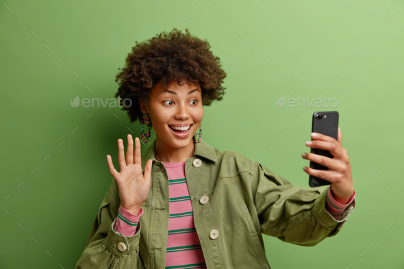 Technology and online lifestyle concept. Smiling African American woman says hi enjoys video calling