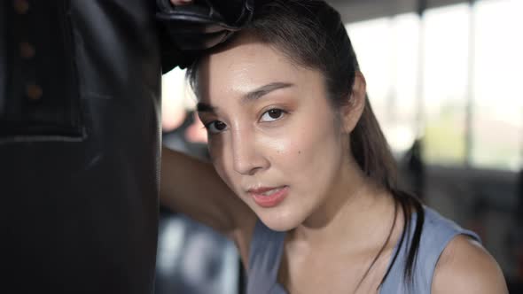 4K Asian sportswoman in sportswear wearing boxing gloves do boxing exercise at gym. alt