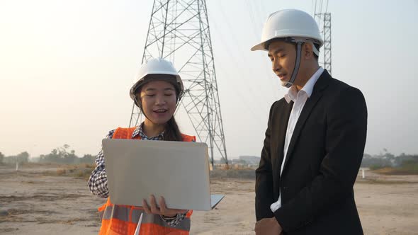 Two Asian engineers inspected the construction site project at a power plant at sunset. Teamwork