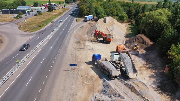 Trucks pouring out granite stone. Heavy machinery carry metal for construction alt
