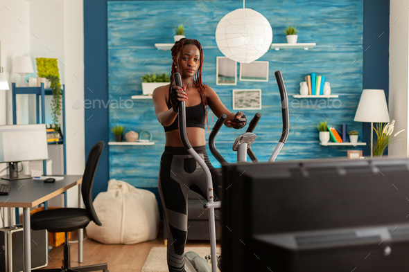African fit strong woman doing cardio exercise on eliptical machine