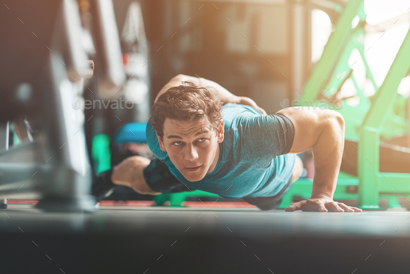 Focus on your fitness. Young man in sportswear exercising indoors. Copy space in upper left part
