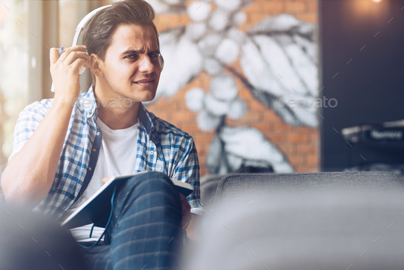 What did you say? Cheerful guy in casual wear listening to music. Copy space on the right side
