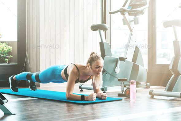 Work harder. Fitness girl doing plank at a gym. Copy space in upper left part