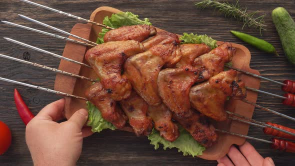 Top View of Hands Placing Fried Chicken Wings on the Table Next to Vegetables alt