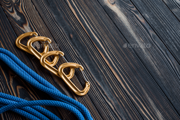 Isolated photo of climbing equipment. Part of carabiner lying on the wooden table