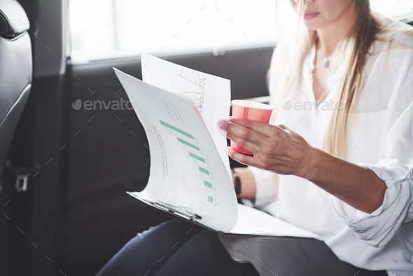 Some paperwork. Beautiful blonde girl sitting in the new car with modern black interior
