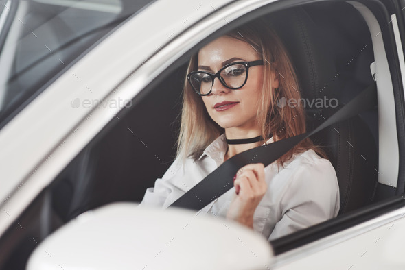 Safety first. Woman in official clothes trying her new car in automobile salon