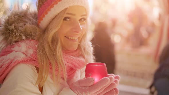 Beautiful young woman with glowing candle in hands