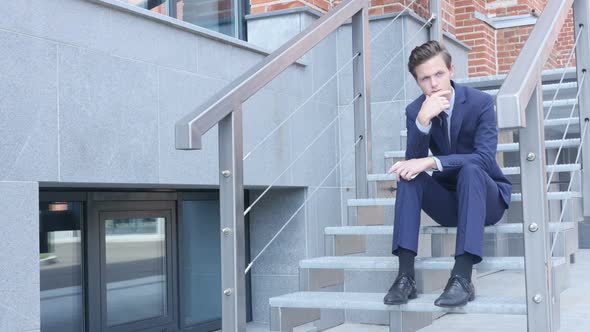Pensive Thinking Young Businessman Sitting on Stairs Outside Office alt