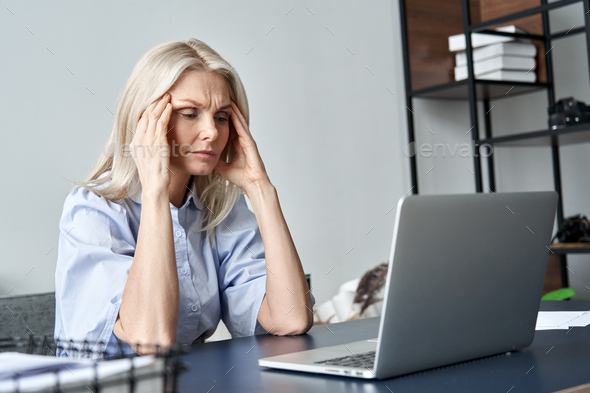 Stressed old business woman suffering from headache after computer work. - Stock Photo - Images