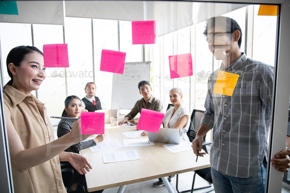 Business people meeting at office with use post it notes on clear board to share idea working.