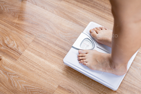 Top view of feet on weighing scale. Women weigh on a weight