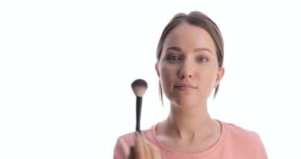 Portrait of Young Caucasian Woman Making Blush on the Face Using Makeup Brush