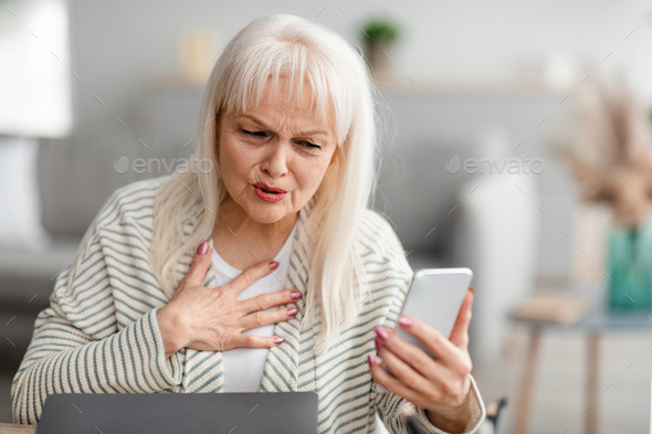 Surprised shocked mature woman using mobile phone Stock Photo by ...