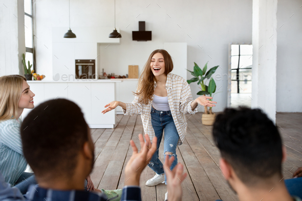 Group of multiethnic friends playing guess who game in modern apartment