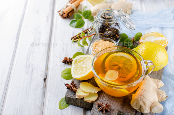 glass cup of hot tea with ginger and lemon, cinnamon sticks, lemon slices, Teapot and brown sugar