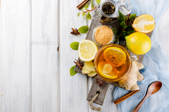 glass cup of hot tea with ginger and lemon, cinnamon sticks, lemon slices, Teapot and brown sugar
